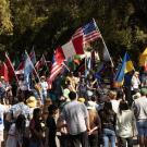A group of people gathered outside holding up different flags from over 20 countries.